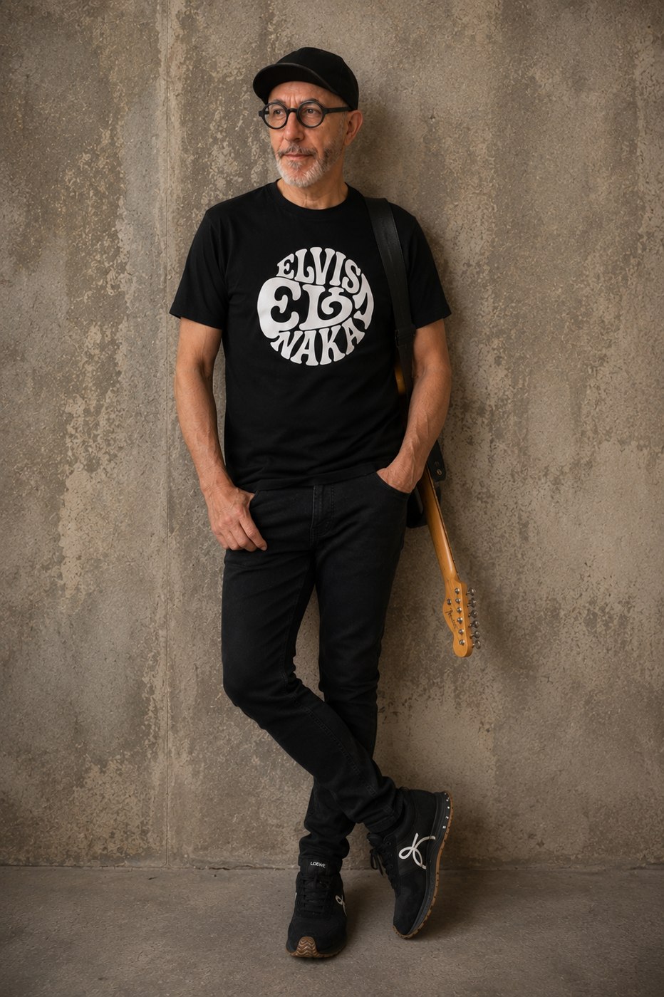 Elvis Naka con la camiseta oficial del logo, apoyado en la pared con la Telecaster